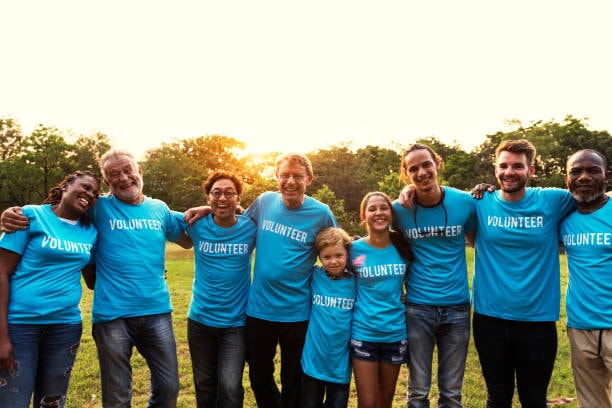 Diverse group of volunteers in blue shirts smiling together outdoors